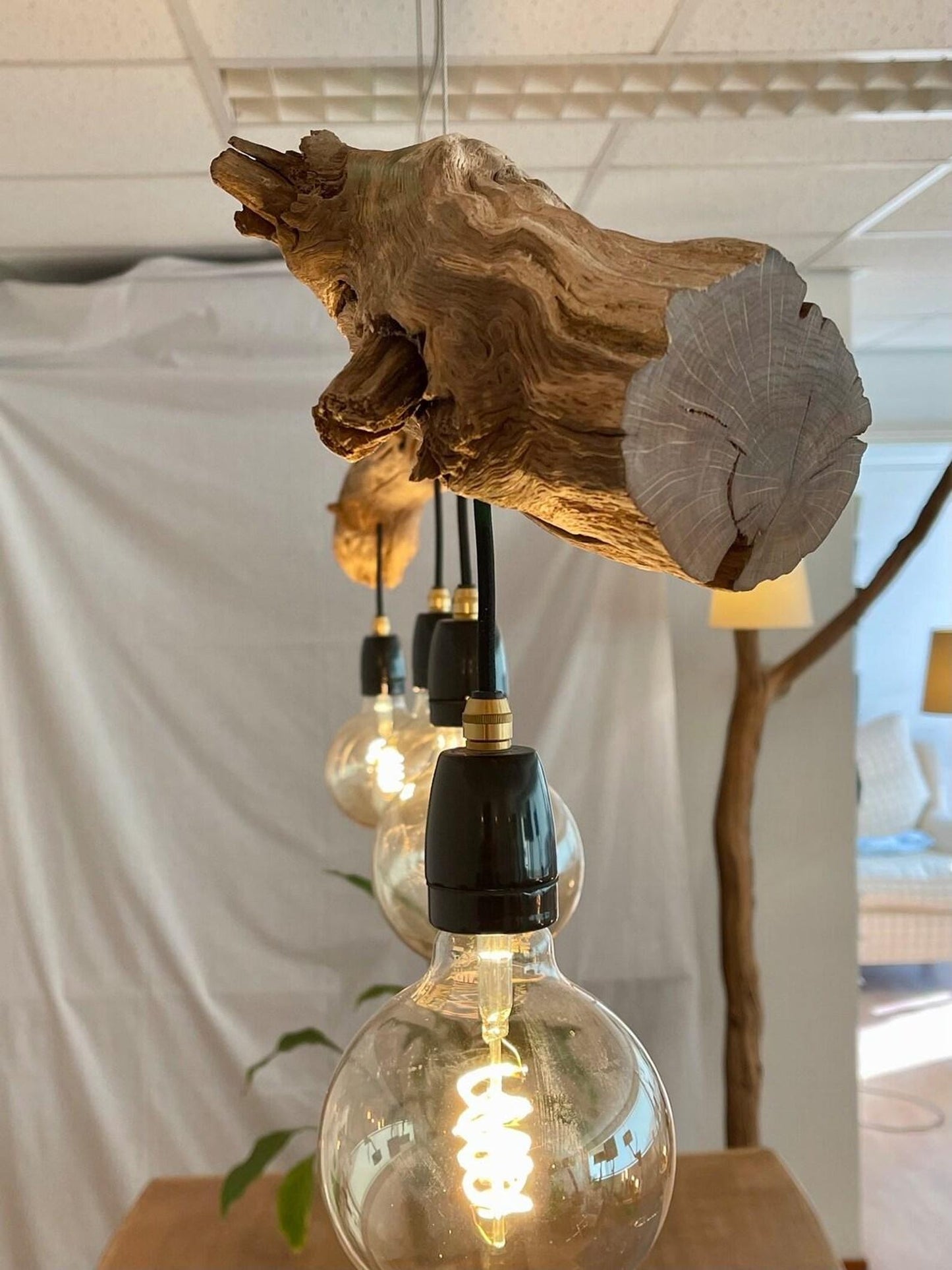 A rustic driftwood ceiling lamp crafted from natural wood branches, suspended by cords and featuring exposed warm-tone bulb lights—ideal for bringing organic farmhouse charm to indoor spaces-3