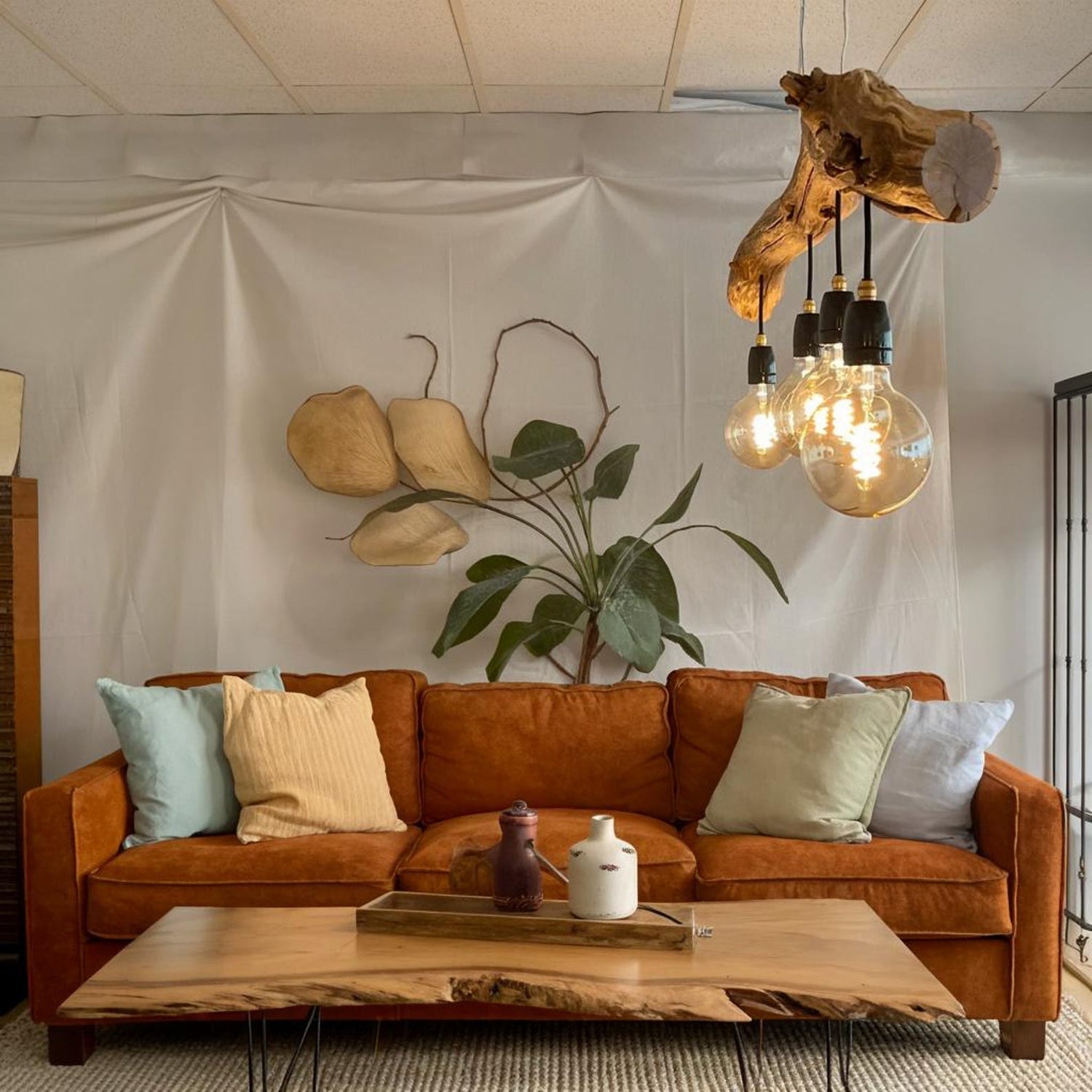 A rustic driftwood ceiling lamp crafted from natural wood branches, suspended by cords and featuring exposed warm-tone bulb lights—ideal for bringing organic farmhouse charm to indoor spaces