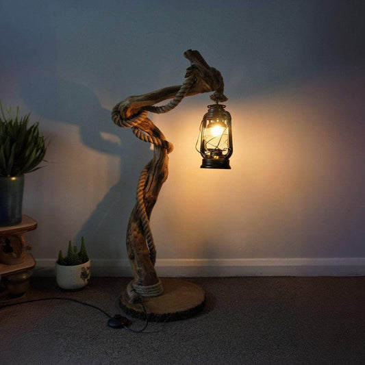 A handcrafted rustic driftwood floor lamp with natural wood base and a beige linen shade, positioned in a living room corner creating warm ambient lighting perfect for both home and office settings